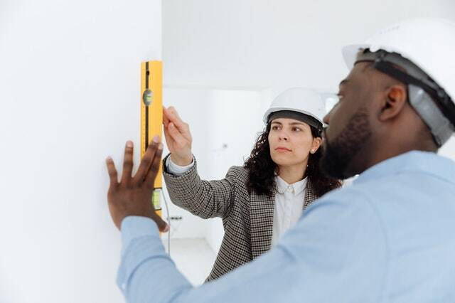 two people in hard hats using a level on a wall